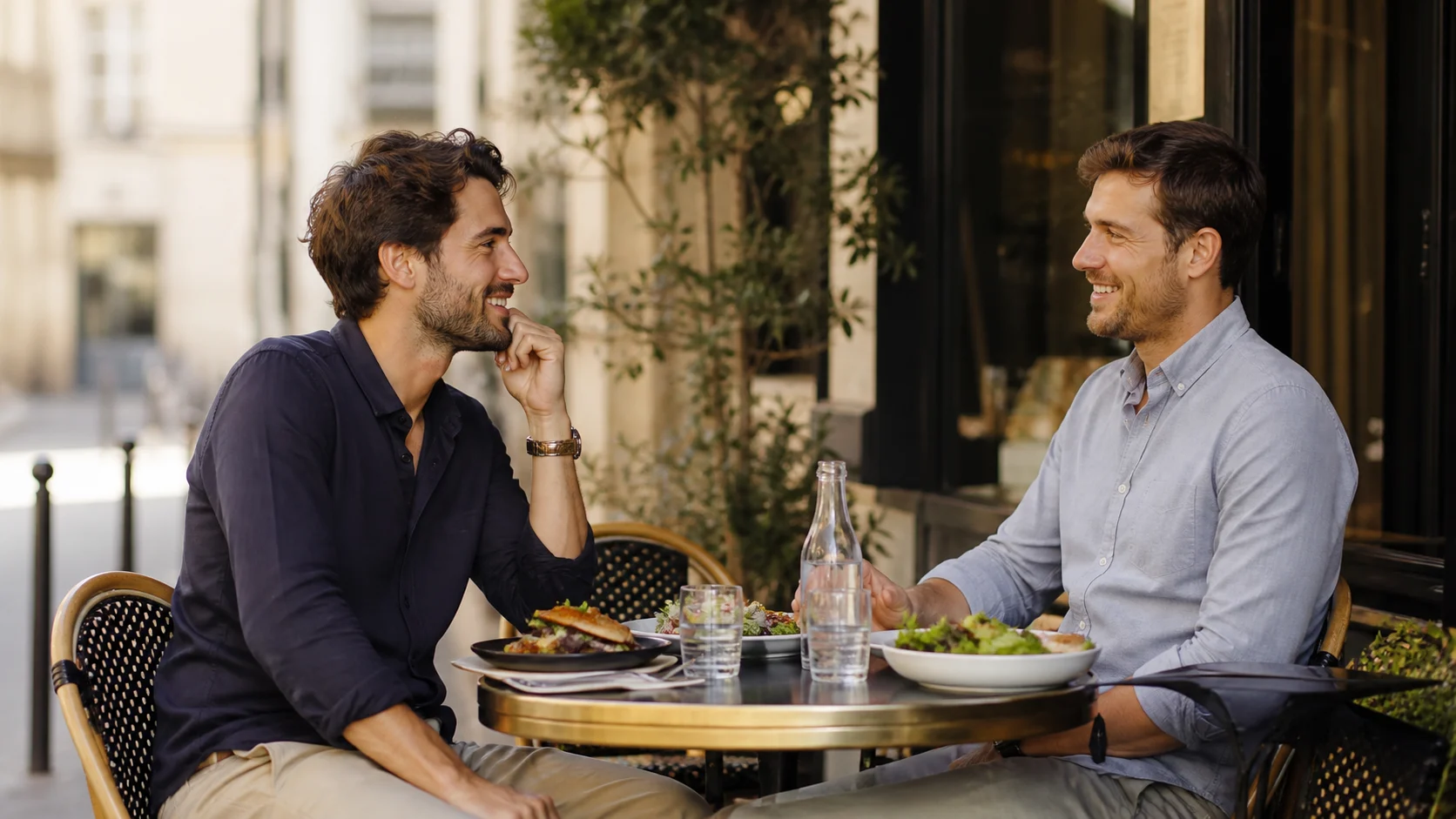 Deux hommes adultes échangeant lors d’un premier rendez-vous à la terrasse d’un café le midi